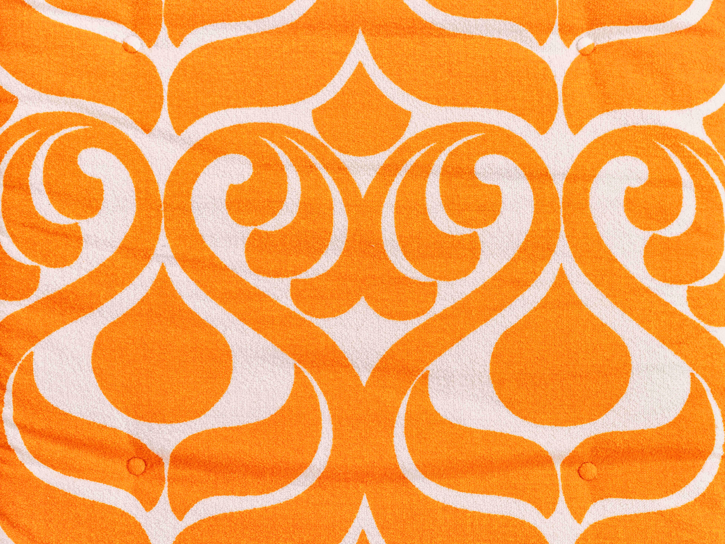 Gros plan du tissu éponge vintage du matelas de plage Sirocco ’71, motif orange et blanc des années 70 avec boutons recouverts