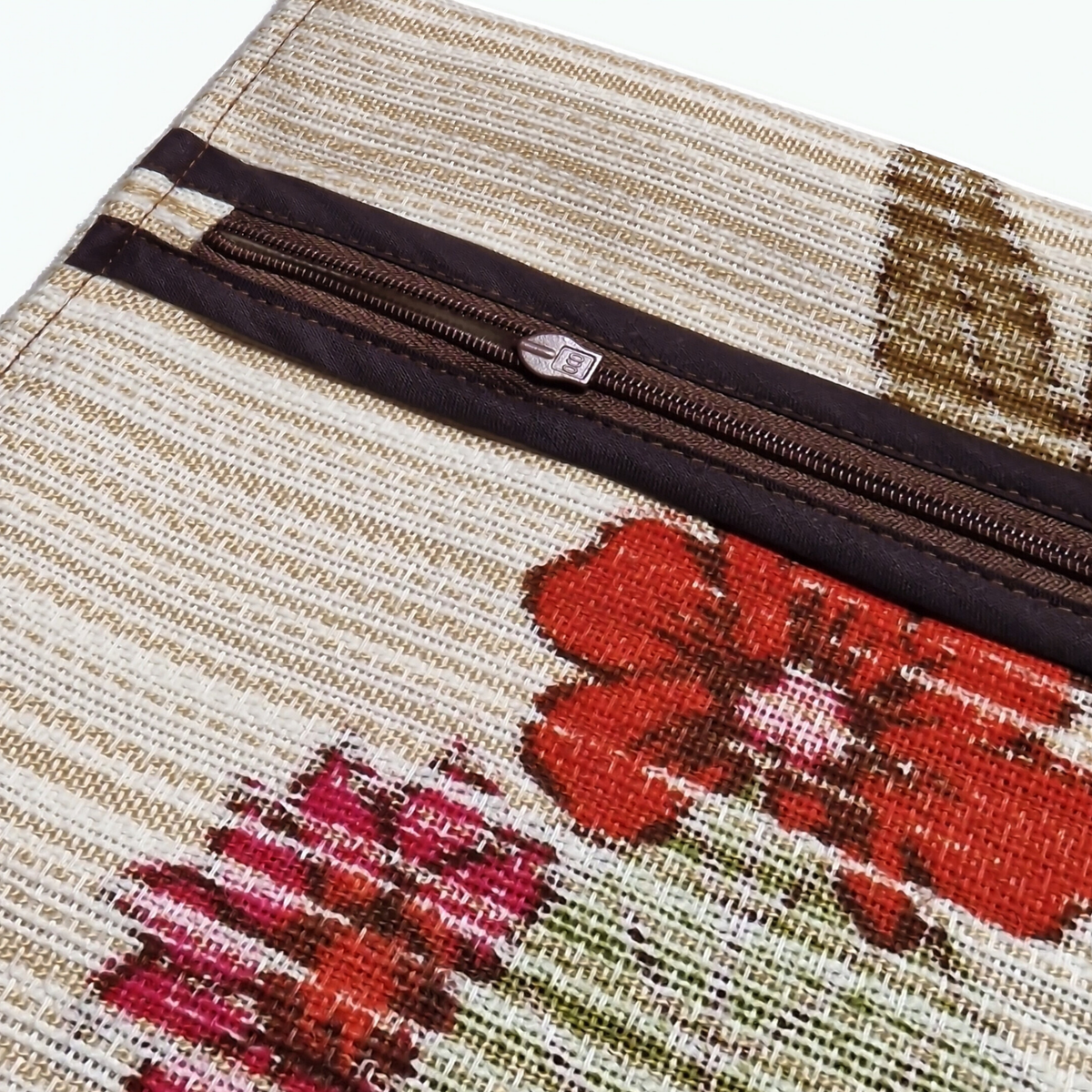 Détail de confection du coussin Dahlia avec fermeture éclair brune et finition soignée sur tissu vintage fleuri