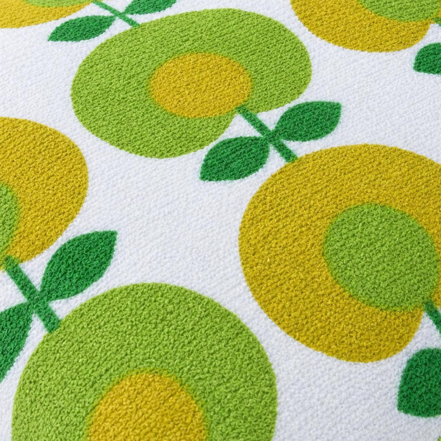 Gros plan du tissu éponge vintage du coussin de plage Oliva ’71, motif floral vert, jaune et blanc des années 70