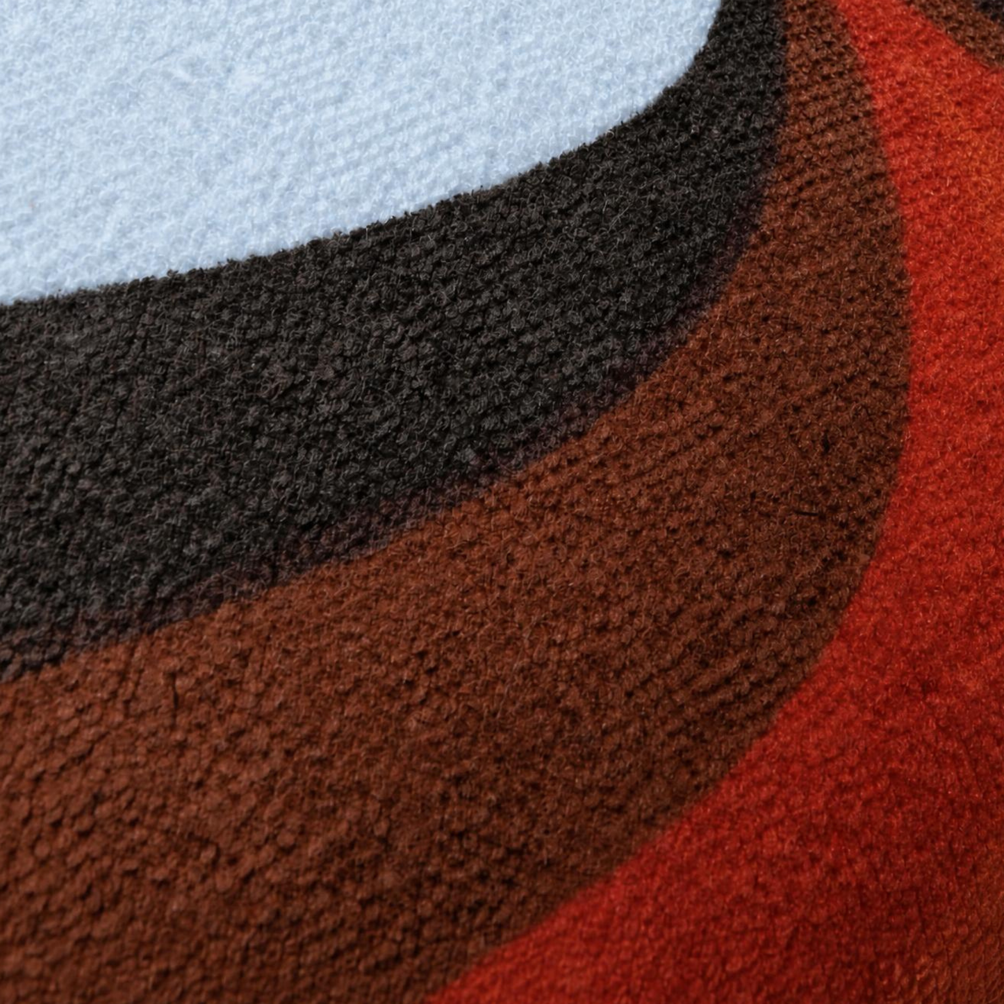 Gros plan du tissu éponge vintage du coussin de plage Riviera ’74, motif géométrique orange, marron et blanc des années 70
