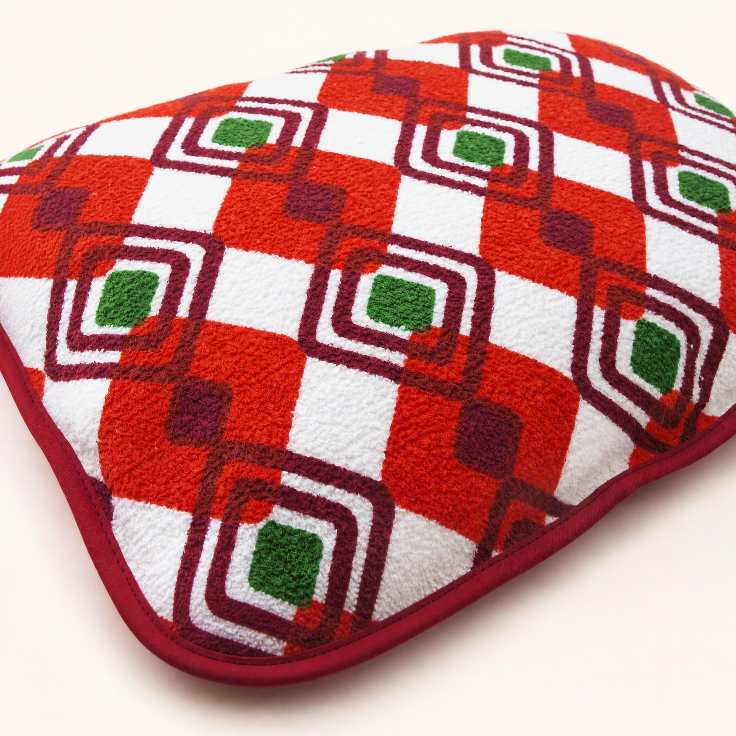 Détail du coussin de plage vintage Ruby ’72 en tissu éponge rouge, orange, vert et blanc, motif géométrique et finition en biais bordeaux