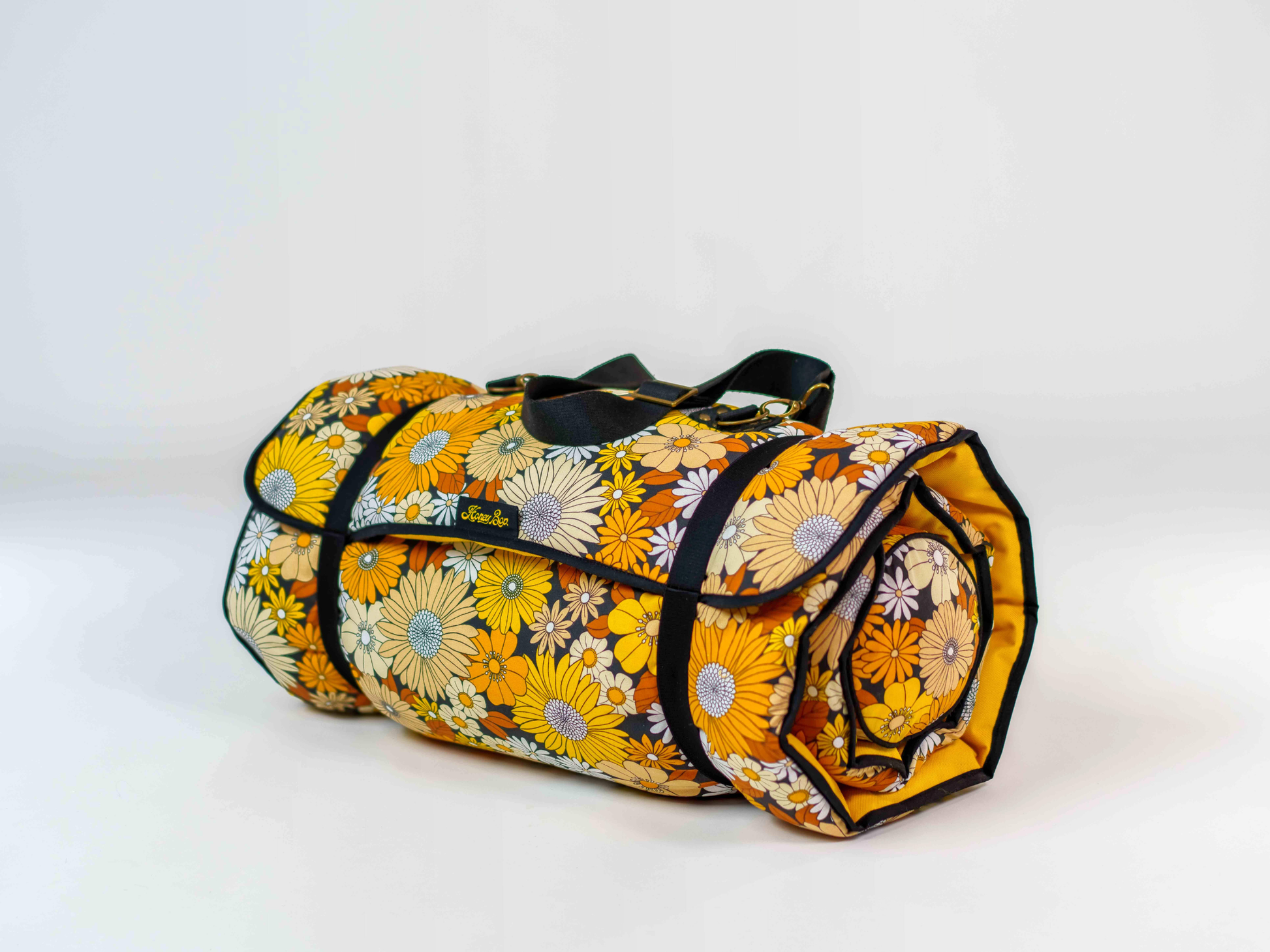 Matelas de plage Golden Bloom ’72 roulé avec sangle de transport amovible, à motif floral jaune, blanc et marron d’inspiration années 70