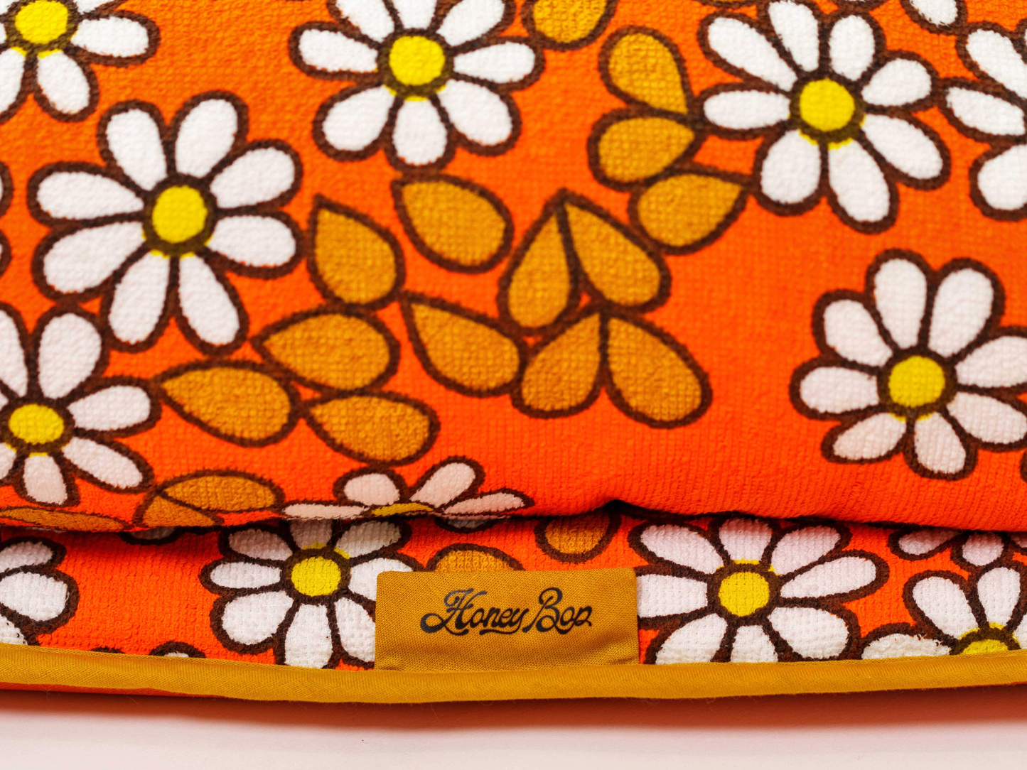 Détail du tissu éponge vintage du matelas de plage Daisy ’73, motif marguerites orange, blanc et jaune des années 70 avec étiquette Honey Bop