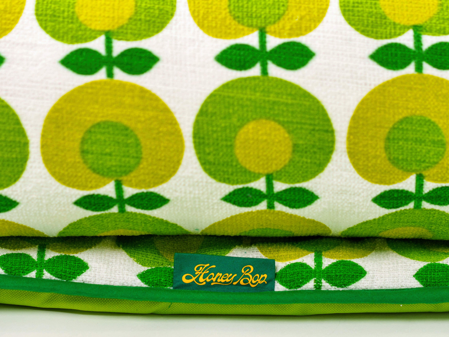 Détail du tissu éponge vintage du matelas de plage Oliva ’71, motif floral vert et jaune des années 70 avec étiquette Honey Bop