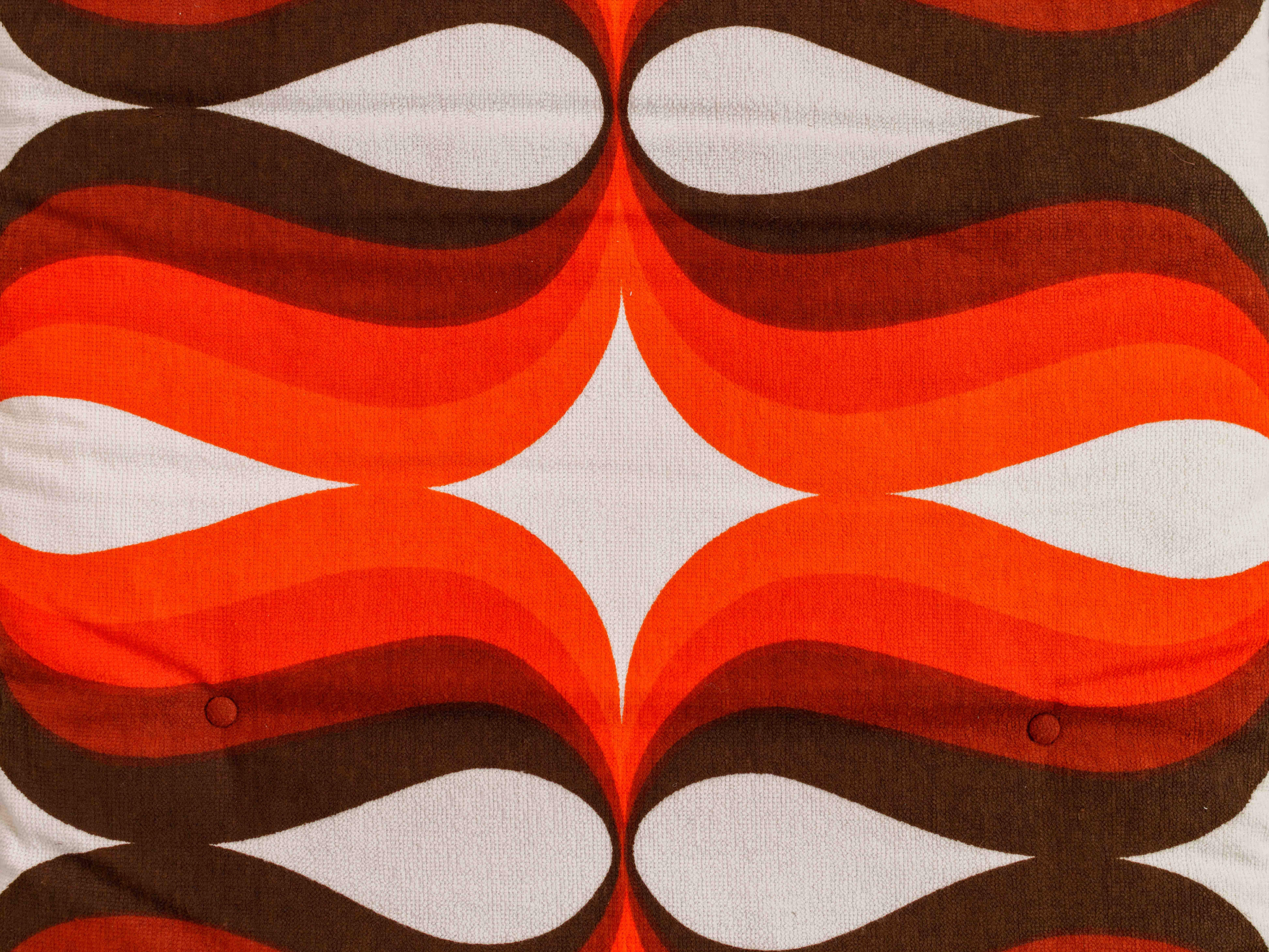 Gros plan du tissu éponge vintage du matelas de plage Riviera ’74, motif géométrique orange, marron et blanc des années 70 avec boutons recouverts