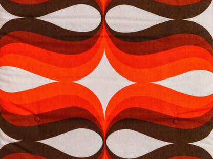 Gros plan du tissu éponge vintage du matelas de plage Riviera ’74, motif géométrique orange, marron et blanc des années 70 avec boutons recouverts