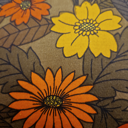 Détail du tissu vintage en coton du coussin Harvest Bloom avec fleurs orange et jaunes sur fond marron