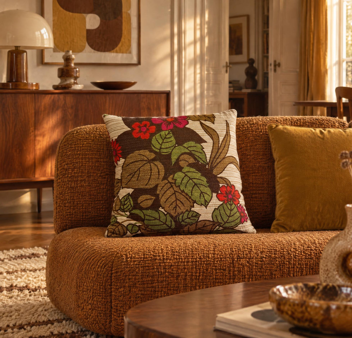 Coussin vintage Dahlia Honey Bop présenté sur un canapé brun dans un intérieur chaleureux d’inspiration années 70