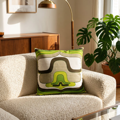 Coussin d’intérieur vintage Orbit Green 40 × 40 cm présenté sur un fauteuil dans un salon d’inspiration années 70